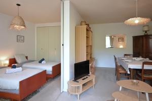 a room with two beds and a living room with a tv at Le Gîte de l’Estuaire - Proche Plage in Saint-Georges-de-Didonne