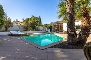 a swimming pool with a palm tree and a house at Villa avec piscine in Cabestany