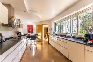 a kitchen with white cabinets and a large window at Villa avec piscine in Cabestany
