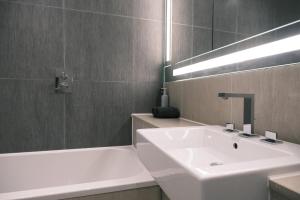 a bathroom with a white sink and a bath tub at Luxury 1BR with Balcony & City Views near Aldgate in Moffat +5 photos