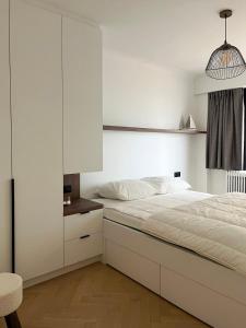 a white bedroom with a bed and a chair at Zeezicht Blankeduyn in Blankenberge
