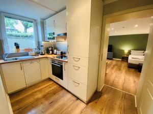 a kitchen with white cabinets and a wooden floor at Amaroo - Apartments "Andy" in Potsdam