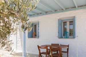 a table and chairs in front of a house with blue windows at Ergina Summer Resort in Antiparos