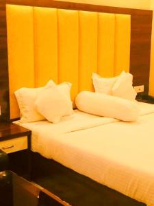 a bed with white pillows on top of it at Red Rose Resort in Mandarmoni