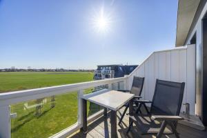 two chairs and a table on a balcony with a field at Resort Deichgraf Resort Deichgraf 27-21 in Wremen