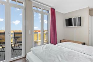 a bedroom with a bed and a balcony at Resort Deichgraf Resort Deichgraf 27-21 in Wremen