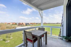 a patio with a wooden table and chairs on a balcony at Resort Deichgraf Resort Deichgraf 31-13 in Wremen