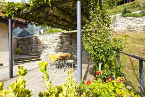 un patio con mesa, sillas y algunas flores en Casa Lumaca, en Cannero Riviera