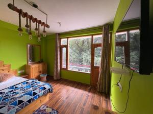 ein Schlafzimmer mit grünen Wänden, einem Bett und Fenstern in der Unterkunft Jack of all in Manali
