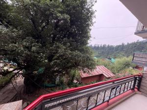 einen Balkon eines Hauses mit einem Baum in der Unterkunft Jack of all in Manali