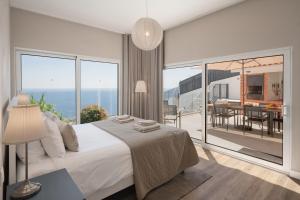 una camera da letto con un letto grande e un balcone di OurMadeira - Villa Aquarela, panoramic seaviews a Caniço Altre 30 foto