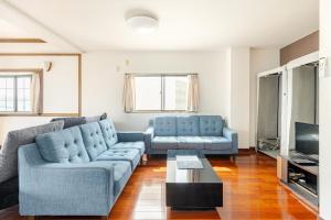 福冈Fieldnever Apartment STAY - Maisonette Family room的客厅配有2张蓝色沙发和电视