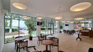 a restaurant with tables and chairs and windows at Hotel Diana in Eforie Nord