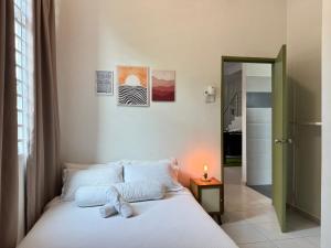 a bedroom with a white bed with a candle on it at A home with private pool, KebunStorey in Tangga Batu +55 photos
