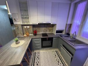 a kitchen with white cabinets and a wooden counter top at Katy Boulevard Apartman in Satu Mare