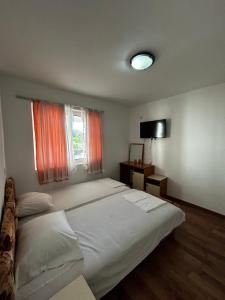 a bedroom with a large white bed and a window at Apartmani Musić in Ulcinj