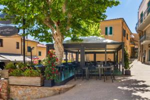 a restaurant with tables and chairs under a tree at Appartamenti Remota in Castiglione della Pescaia