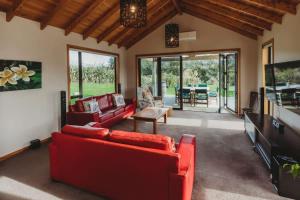 a living room with red couches and a table at Serenity Lodge Getaway - with river views in Egmont Village
