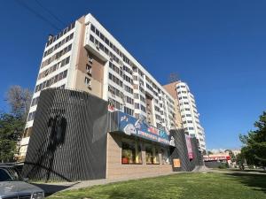 a tall white building with a sign in front of it at Уютный уголок кв 54 in Shymkent