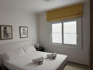 a white bedroom with a bed with towels on it at Apartamento Pineda de Mar en Primera Línea in Pineda de Mar