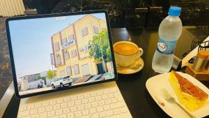 un computer portatile appoggiato su un tavolo con un piatto di cibo e una bevanda di LeLodge Djibouti a Gibuti