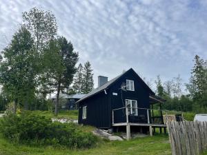 SandöverkenGrindstugan的黑房子,在田野上设有甲板