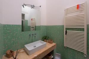 Un baño de azulejos verdes con lavabo y espejo. en La casa di Annetta, en Montalcino