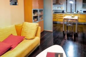 Una sala de estar con un sofá amarillo y una cocina. en La casa di Annetta, en Montalcino