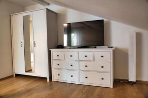 a white dresser with a television on top of it at Ferienwohnung Im Münchner - Süden in Schäftlarn