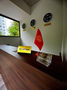 a room with a reception desk with a flag and clocks at Asia Hotel Osh in Osh