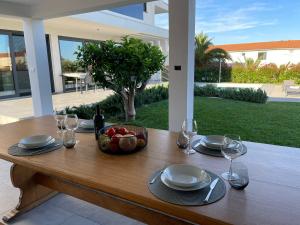 een houten tafel met een schaal fruit en wijnglazen bij Villa Andris-luxury villa near sandy beach - by TRAVELER tourist agency KRK in Ližnjan