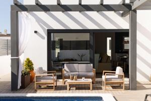 a patio with a couch and chairs and a table at Villa Sal - Porto Covo in Porto Covo