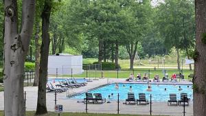 a swimming pool with people sitting in chairs in a park at Hengelhoef Berk 5 in Aan de Wolfsberg
