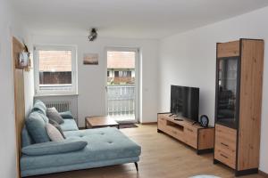 a living room with a blue couch and a tv at Ferienwohnung Eder in Bad Birnbach