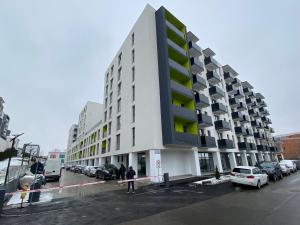 a large white building with cars parked in a parking lot at Owl's Nest Apartment in Cluj-Napoca