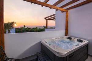 a jacuzzi tub on a balcony with a sunset at Martini Boutique Resort in Ialysos