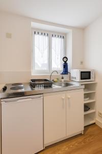 een witte keuken met een spoelbak en een magnetron bij Le Cozy - Hyper centre - Calme - Moyenne durée in Épinal