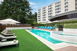 a swimming pool with lounge chairs and a building at Sheraton Milan San Siro in Milan