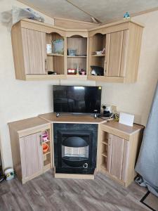 Una sala de estar con televisión y chimenea. en PMH rental, en Saint Osyth