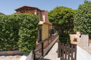a fence with trees in front of a house at Un giardino sul mare in Budoni