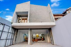 a large white building with glass doors at Hotel O Tegal near near Pacific Mall Tegal formerly Hugo Suites Family in Tegal