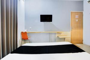 a bedroom with a bed and a desk with a television at Hotel O Tegal near near Pacific Mall Tegal formerly Hugo Suites Family in Tegal