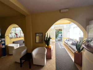eine Lobby mit einem gewölbten Eingang mit weißen Stühlen in der Unterkunft Hotel Fiorenza in Milano Marittima