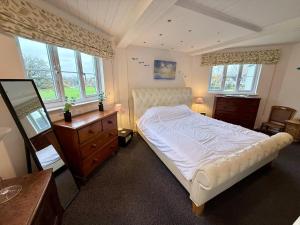 a bedroom with a bed and a dresser and windows at Pepperpot Lakeside Lodge on Isis & Windrush Lakes in the Cotswold Lakes in South Cerney