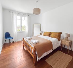 a bedroom with a large bed and a blue chair at Séjour champêtre à la ferme près de Pau in La Celle-sous-Gouzon