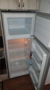 an empty refrigerator with its door open in a kitchen at Konstantinos Apartments in Kholargós