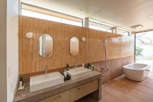ein Badezimmer mit zwei Waschbecken, einer Badewanne und einer Dusche in der Unterkunft Dei Amami in Amami