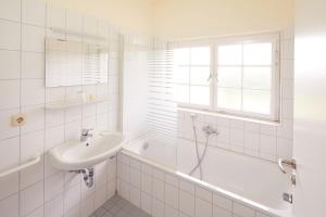 biała łazienka z umywalką i wanną w obiekcie Tagungshotel Wiesenhaus w mieście Künzell