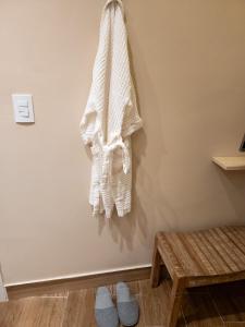 a white towel hanging on a wall with slippers at Green Flats em Miguel Pereira in Miguel Pereira