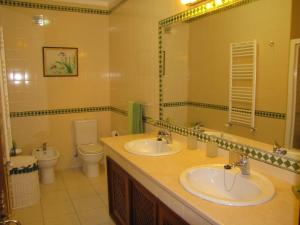 a bathroom with two sinks and a toilet and a mirror at Quinta do Cerquito in Ferreira do Zêzere